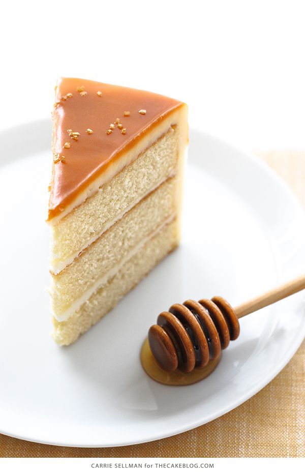 a piece of cake on a plate with a honey stick