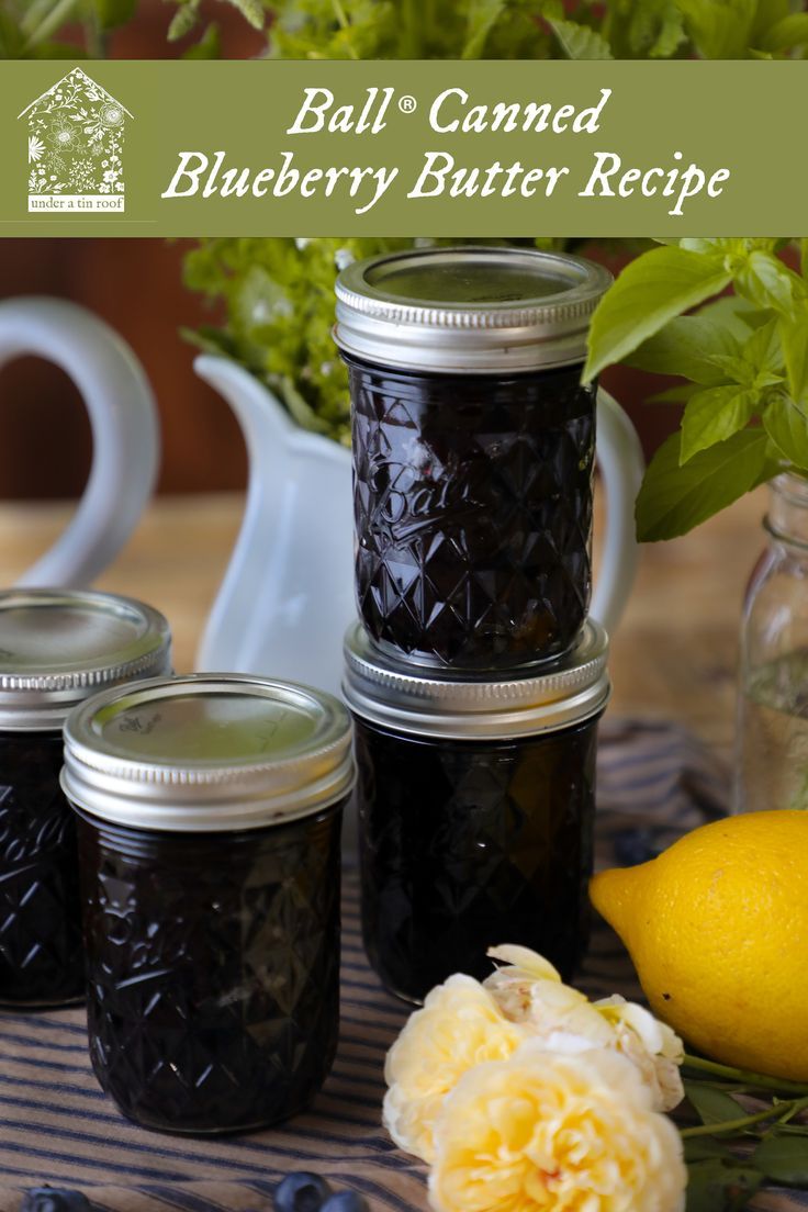 four jars filled with blueberry butter sitting on top of a table next to lemons