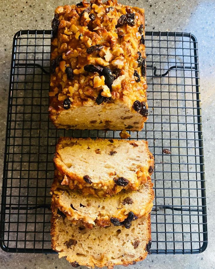 three slices of bread sitting on top of a cooling rack with raisins and nuts