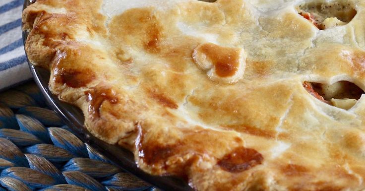 a pie sitting on top of a blue and white place mat next to a wooden spoon