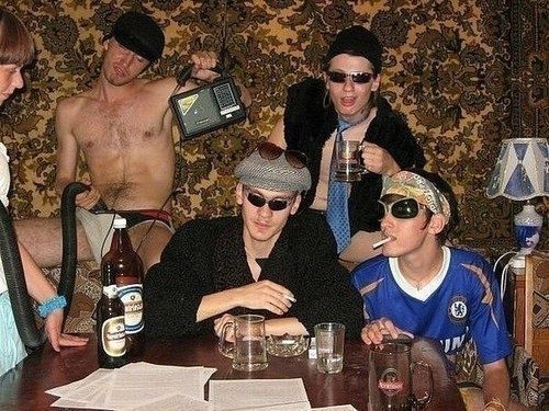 a group of people sitting around a table with bottles and glasses on top of it