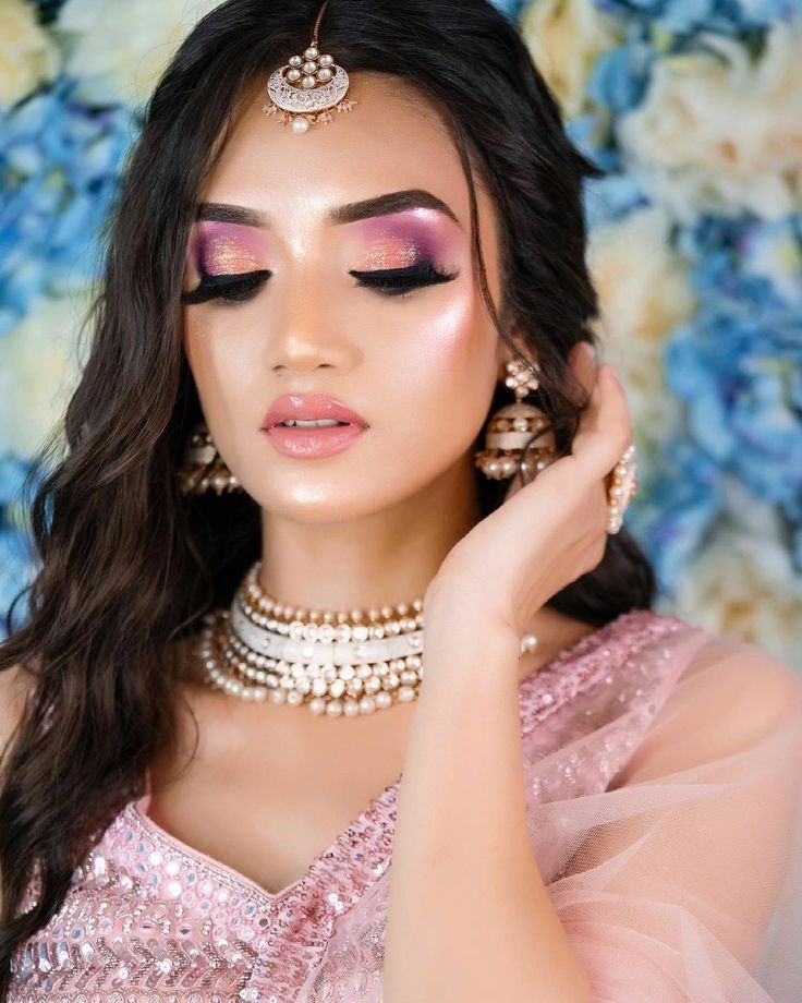 a woman with long dark hair wearing pink makeup