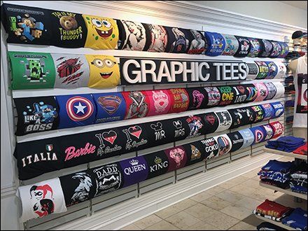 the store has many t - shirts hanging on the wall and in front of it is a sign that says graphic tees