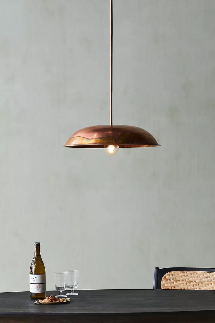 a table with two wine glasses and a bottle on it next to a light fixture