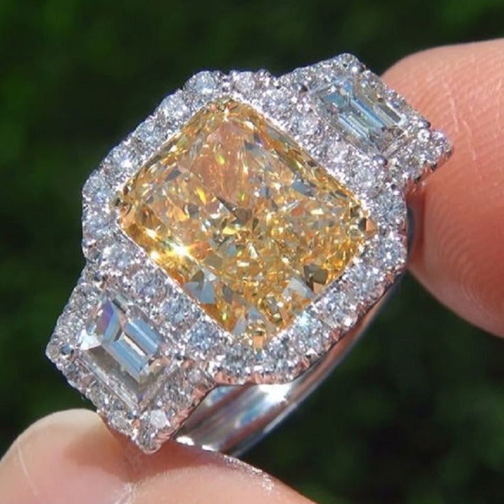 a fancy yellow diamond ring with baguettes on the sides and diamonds around it