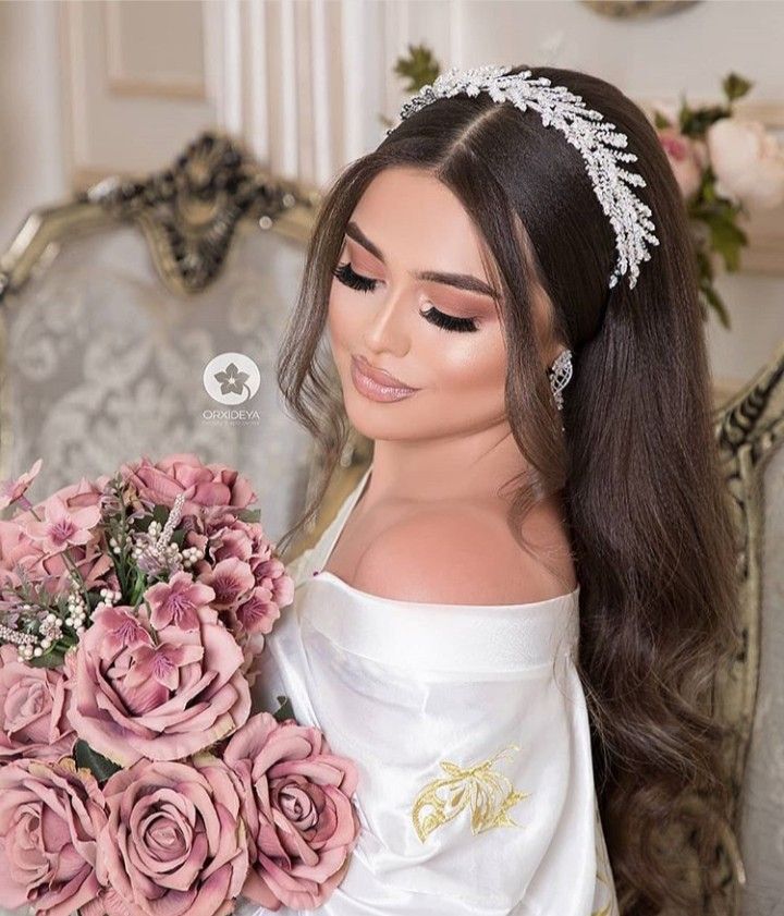 a woman in a white dress holding a bouquet of flowers and wearing a tiara