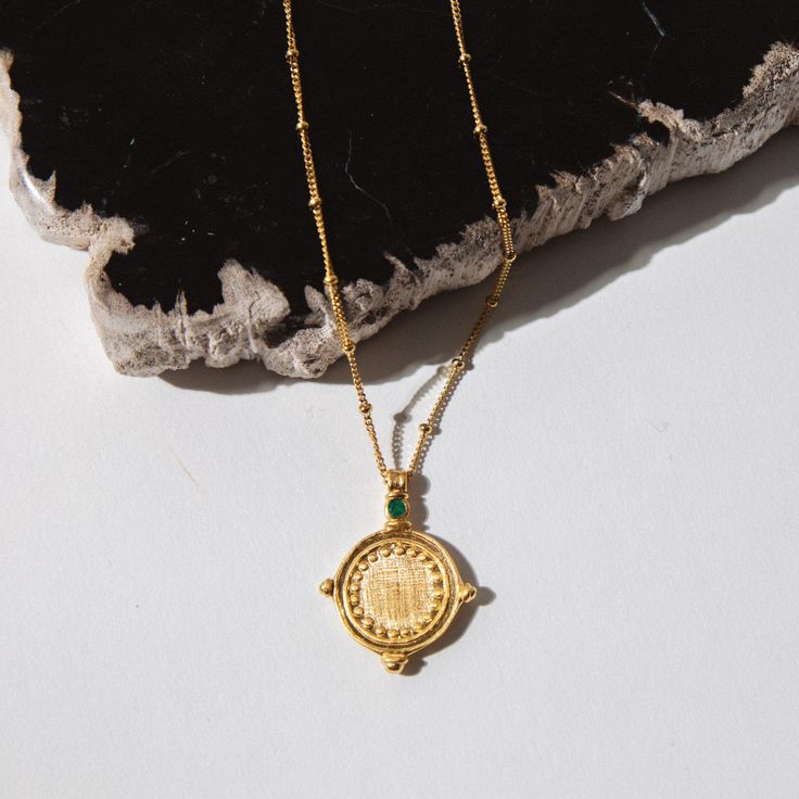 The Sura Necklace in cross-brushed 18K Gold Vermeil is reminiscent of an ancient coin with its embossed detail and circular shape. A faceted oval emerald at the tip of 4 symmetrical points completes the design. Set upon a fine chain enhanced by delicate gold bead elements. Emeralds represent love, wisdom and fertility. A goddess stone. A stone of aspiration and inspiration. Emerald opens the heart, clearing and strengthening one’s connection to Divine Love and sustaining one in their spiritual j Gold Medallion Necklace, Love Wisdom, Child Of Wild, Faith Necklace, Ancient Coin, Jewelry Drawing, Gold Medallion, Medallion Necklace, Ancient Coins