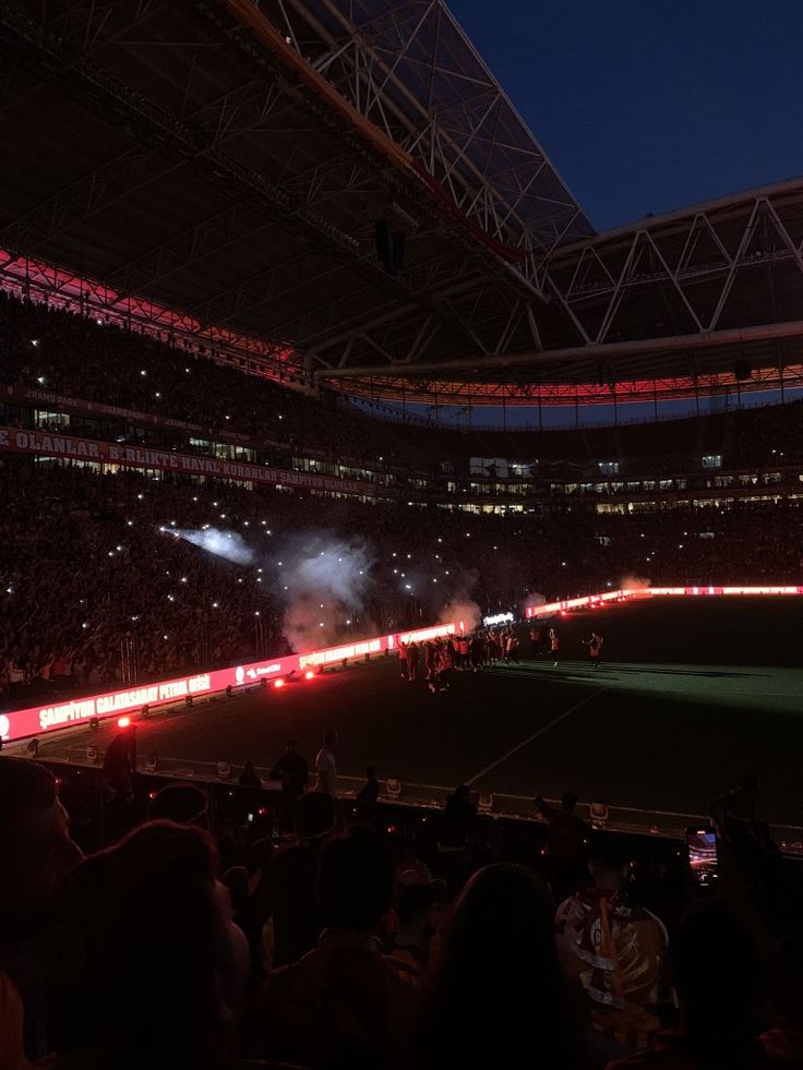 a stadium filled with lots of people watching fireworks go off in the air at night