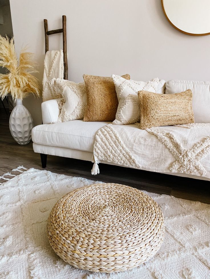 a white couch sitting on top of a wooden floor next to a rug and potted plant