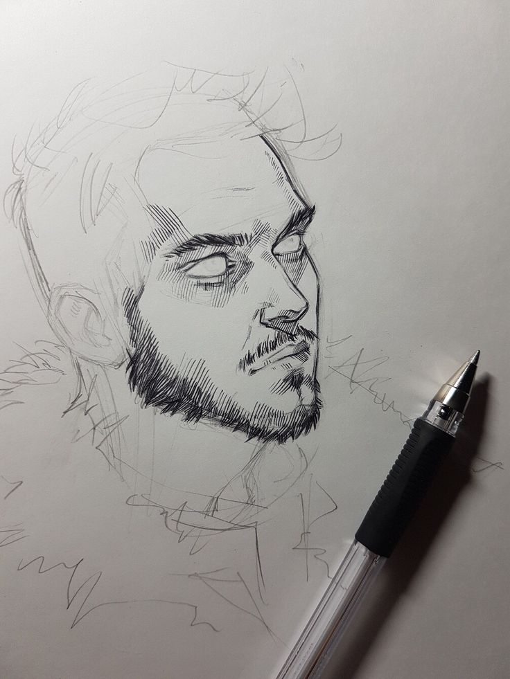 a pencil drawing of a man's face on paper with a pen next to it