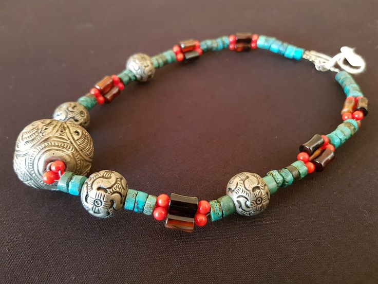 Beautiful handcrafted Tibetan tribal necklace from Lijiang, China. Large Tibetan silver central feature bead with traditional animal motifs. Single strand turquoise barrels and smaller Tibetan silver beads with triple strands of small  coral and larger amber barrels between. A stunning and colourful piece featuring old world stones. Length: 455mm (17.91") Weight: 61g (2.15oz) Traditional Silver Turquoise Round Beads Necklace, Traditional Silver Turquoise Necklace With Round Beads, Traditional Adjustable Turquoise Necklace With Natural Stones, Traditional Beaded Silver Turquoise Necklace, Handmade Silver Turquoise Necklace For Festivals, Bohemian Silver Turquoise Necklace For Festivals, Silver Bohemian Turquoise Necklace For Festivals, Silver Beaded Turquoise Necklace For Festivals, Silver Hand-strung Necklaces For Festivals