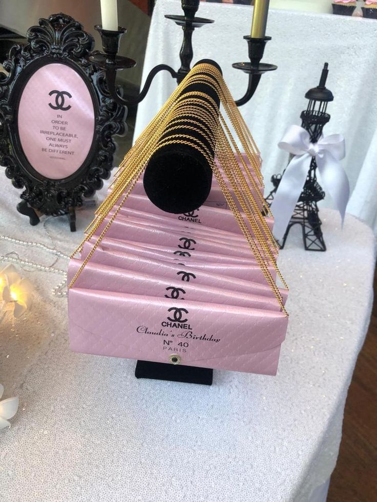 a table topped with pink and gold items on top of a white cloth covered table