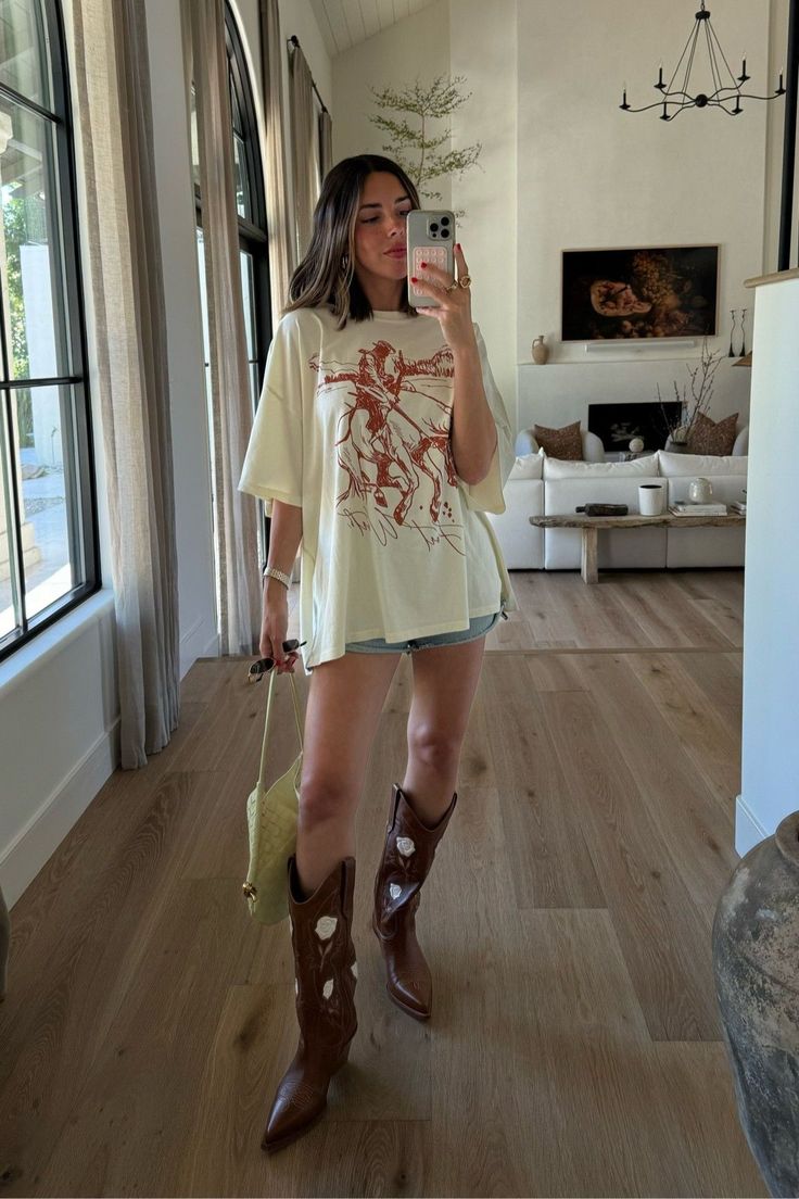 looking for more casual, western inspired outfits for summer? I've got you covered. tap to shop this oversized graphic tee, denim shorts, yellow shoulder bag and brown cowboy boots for summer and check out more of my everyday casual outfits for summer. Texas Summer Outfits, Cowboy Boots Outfit Summer, Traje Cowgirl, Western Inspired Outfits, Summer Boots Outfit, Country Concert Outfits, Cowboy Boot Outfits, Casual Country Outfits, Concert Outfit Ideas