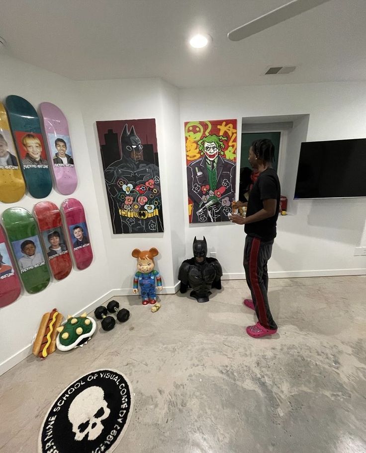 a person standing in a room with skateboards on the wall and stuffed animals around