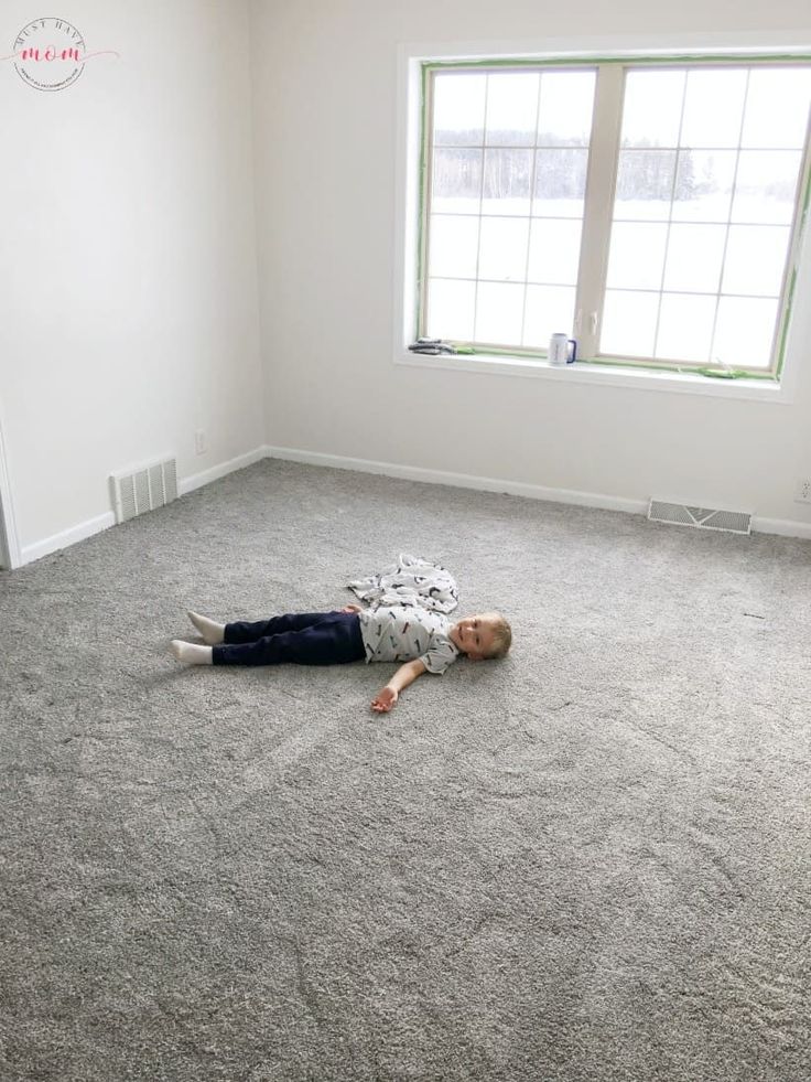 a young boy laying on the floor in an empty room