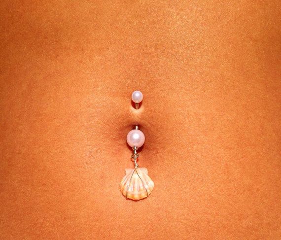 a woman's stomach with two pearls attached to the side and an earring