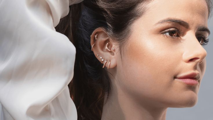 a woman with her hair pulled back and wearing earring in the air, looking off into the distance