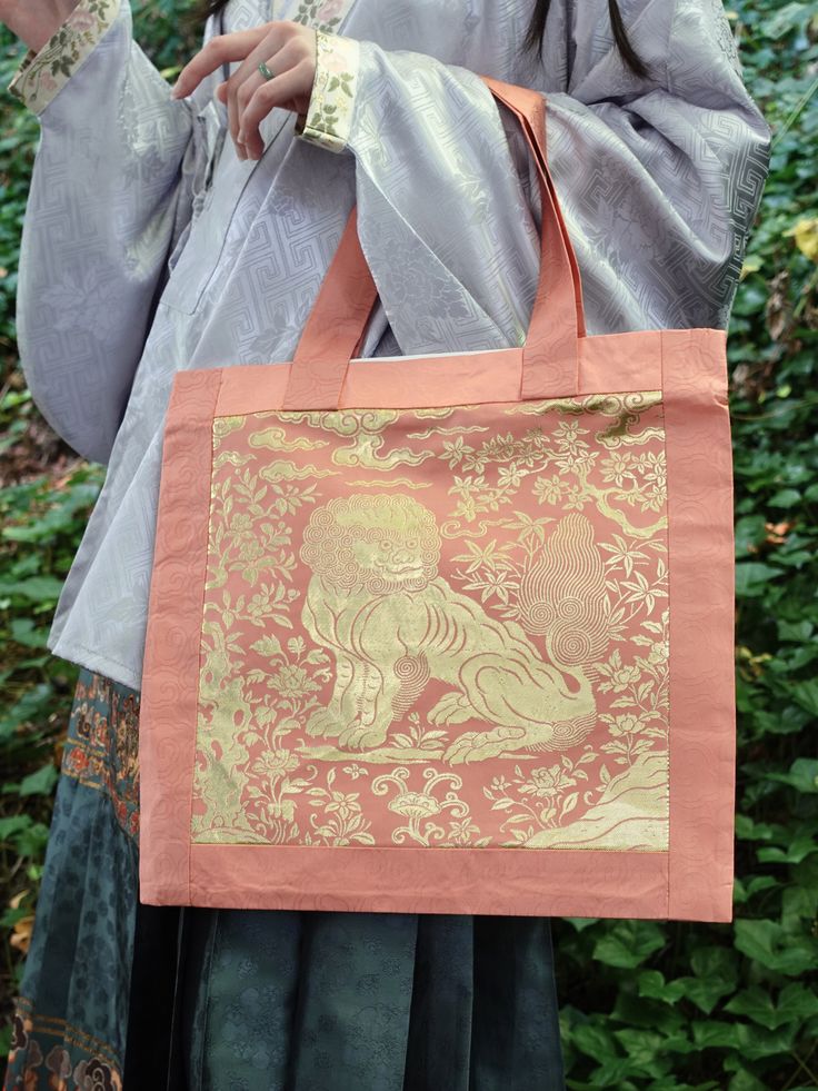 Kiki Bakery x Nüwa Hanfu Mid-Autumn Festival collaboration item! 🥮 A spacious tote bag for all your goddess needs, bring a golden lion to protect you wherever you go! Symbolizing strength and fortune, each tote features an intricately designed Buzi 補子 (Mandarin square) patch on the front. The base fabric itself is embedded with auspicious clouds, adding an extra layer of good fortune for all your belongings. Easily fits books, tablets, pencil cases, waterbottles, and more! Double-lined for dura Kiki Bakery, Golden Lions, Modern Hanfu, Jasmine Tea, Fan Jewelry, Autumn Festival, New Chinese Style, Mid Autumn, Mid Autumn Festival