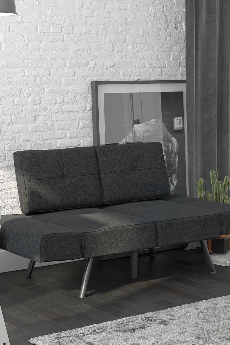 a living room with a gray couch and white brick wall