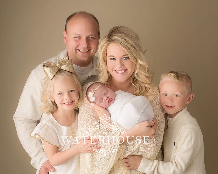 a man, woman and two children are posing for a family photo with their newborn baby