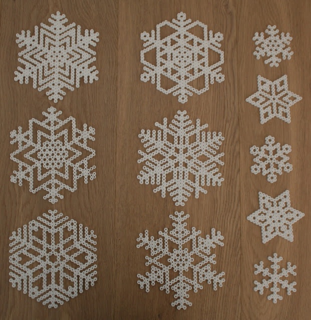 six snowflakes are shown on a wooden surface with white dots in the middle