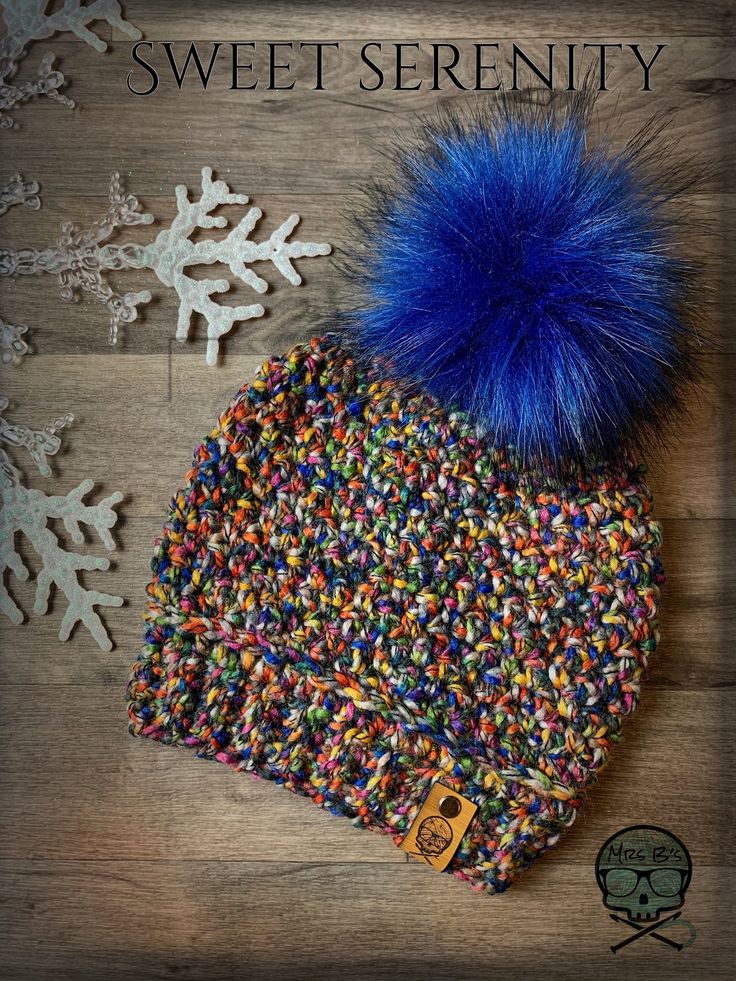 a knitted hat with blue pom - pom sitting on top of snowflakes