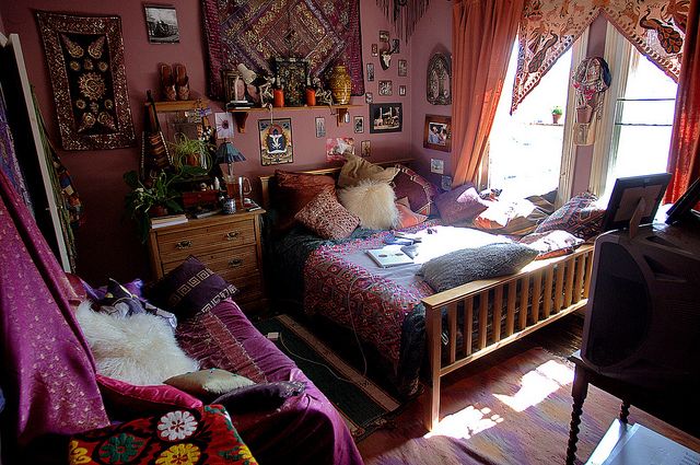 a bed room with a neatly made bed and lots of pictures on the wall above it