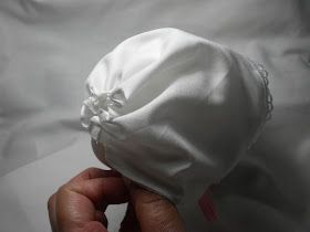 a hand holding a white cloth ball on top of a bed