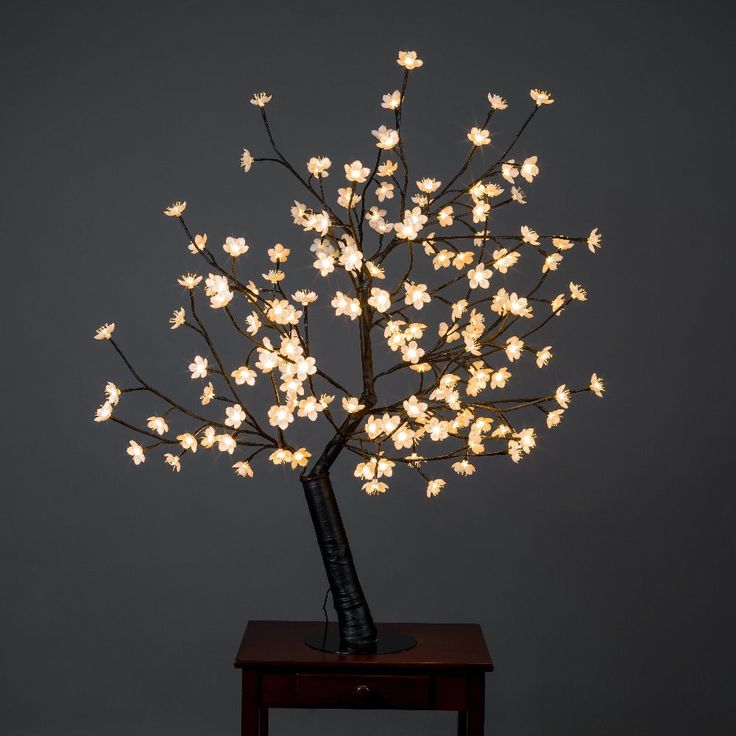 a lighted tree with white flowers on a table