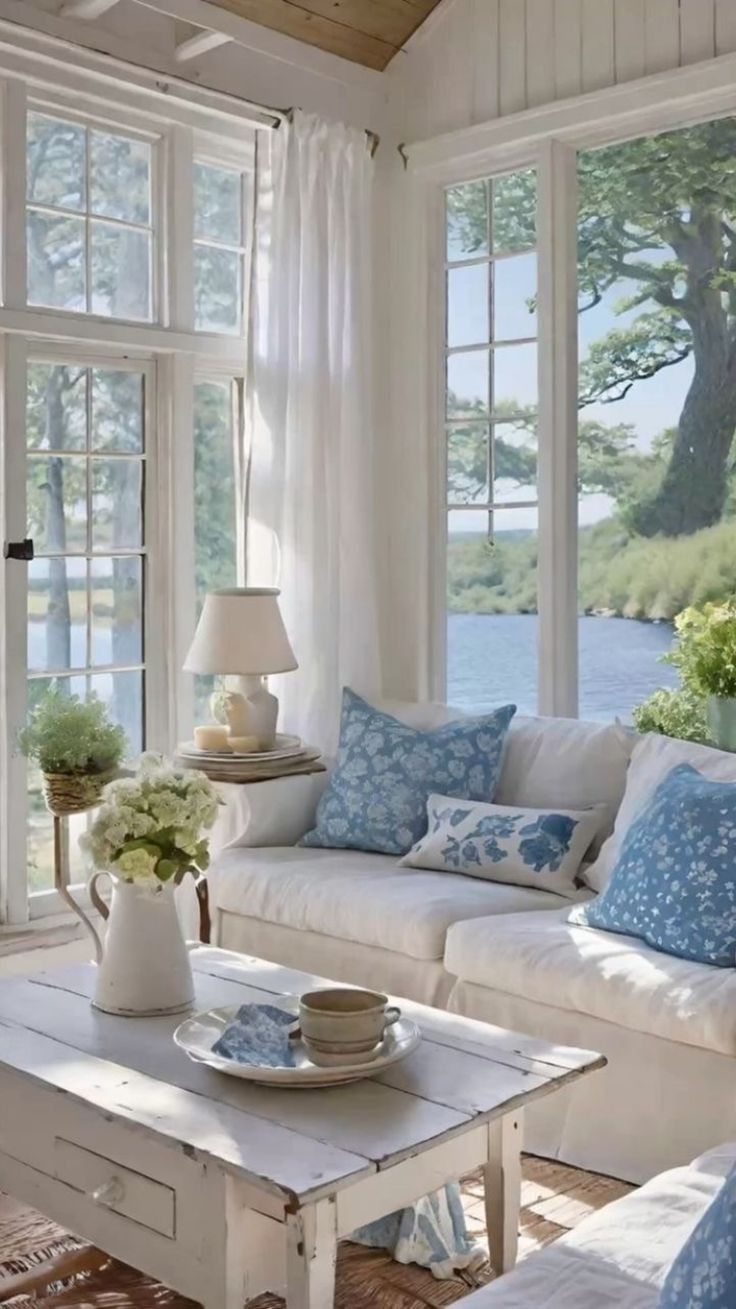 a living room filled with white furniture and lots of windows covered in blue and white curtains