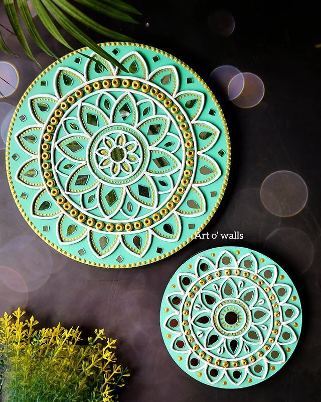 two decorative plates sitting next to each other on top of a black surface with yellow flowers in the background