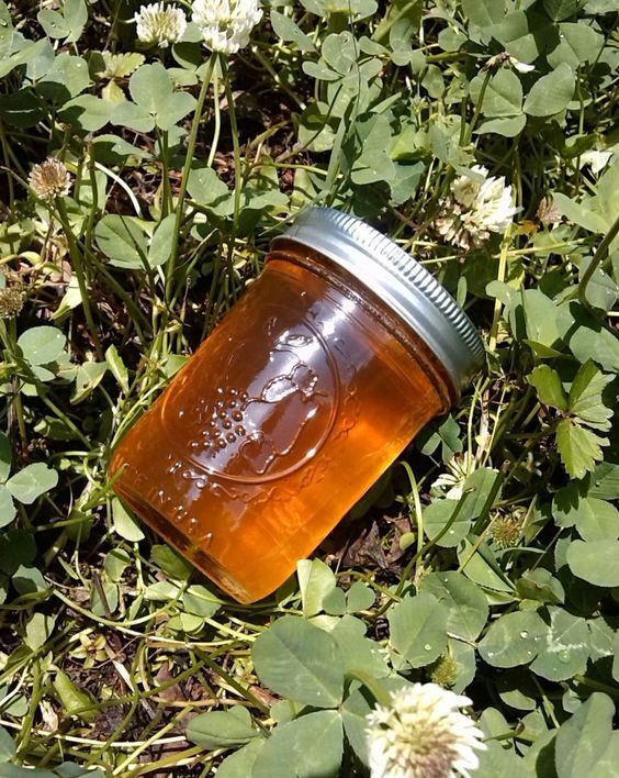 a jar sitting in the grass with flowers around it