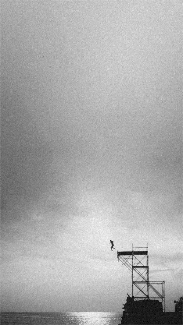 a black and white photo of a person on a surfboard in the air above the ocean