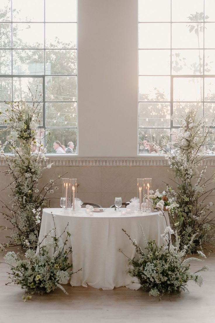 the table is set with candles, flowers and greenery for an elegant wedding reception