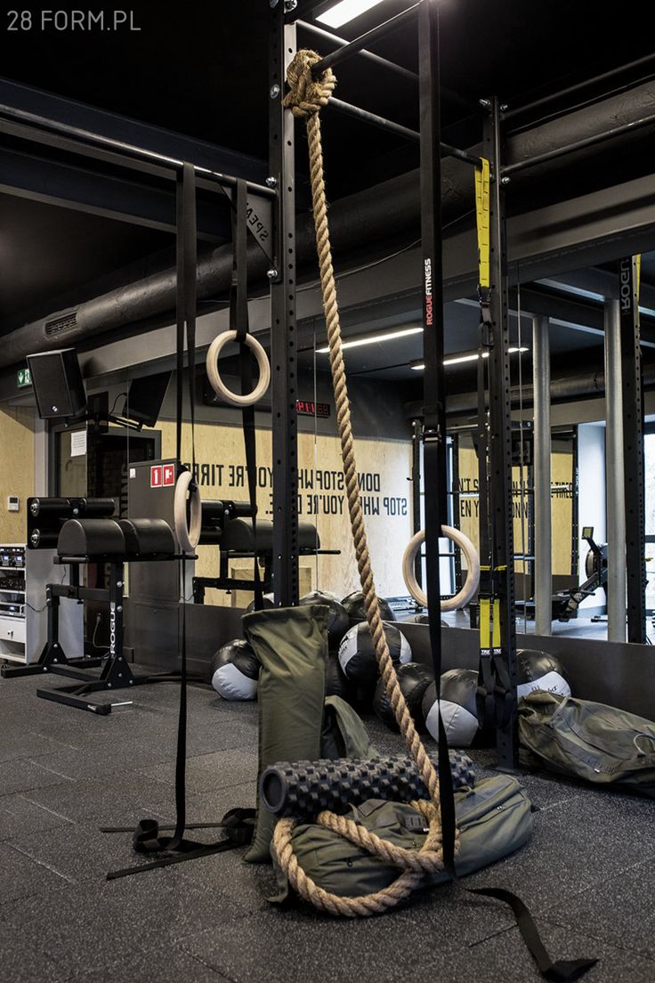 an empty gym with ropes and bags on the ground in front of it, near other equipment