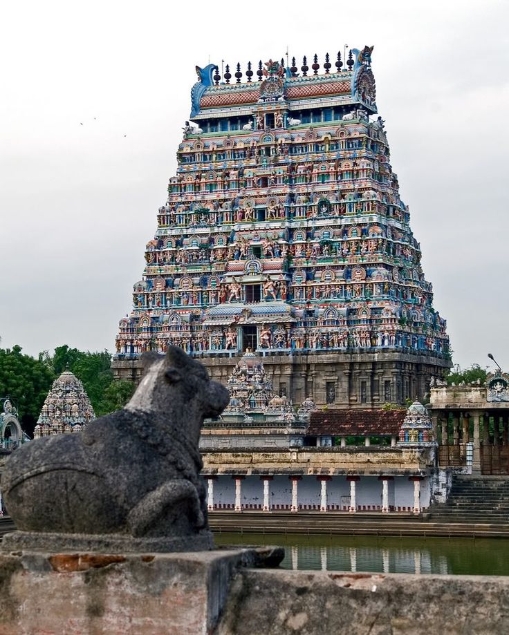 a very tall building that has some statues on it's sides and an elephant statue in the foreground