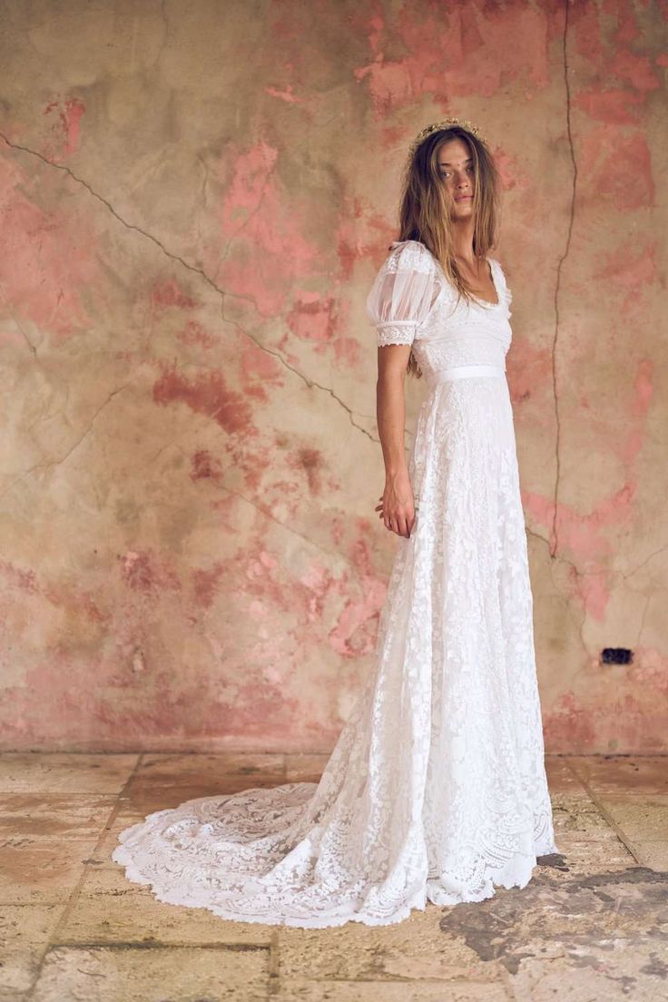 a woman wearing a white dress standing in front of a wall