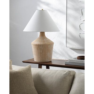 a white lamp sitting on top of a wooden table next to a couch in a living room