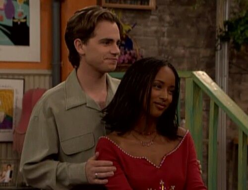 the young man and woman are standing next to each other in front of a staircase