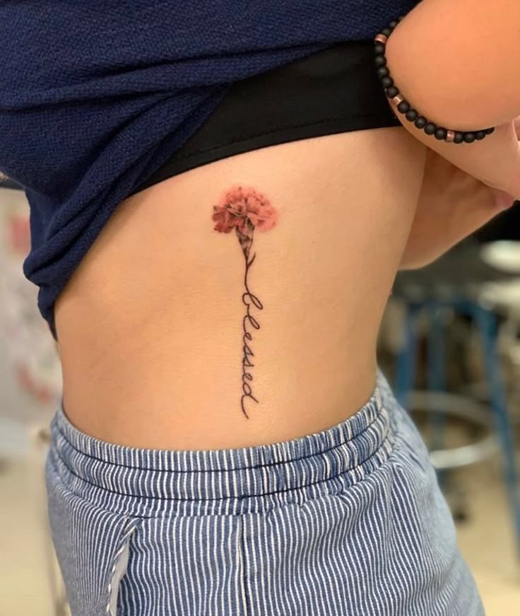 a woman with a flower tattoo on her lower back and the word love written in cursive writing