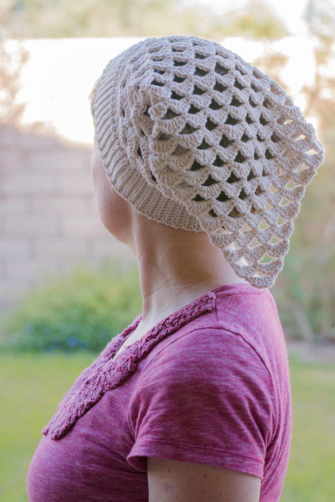 a woman wearing a white crochet hat in the yard with her back to the camera