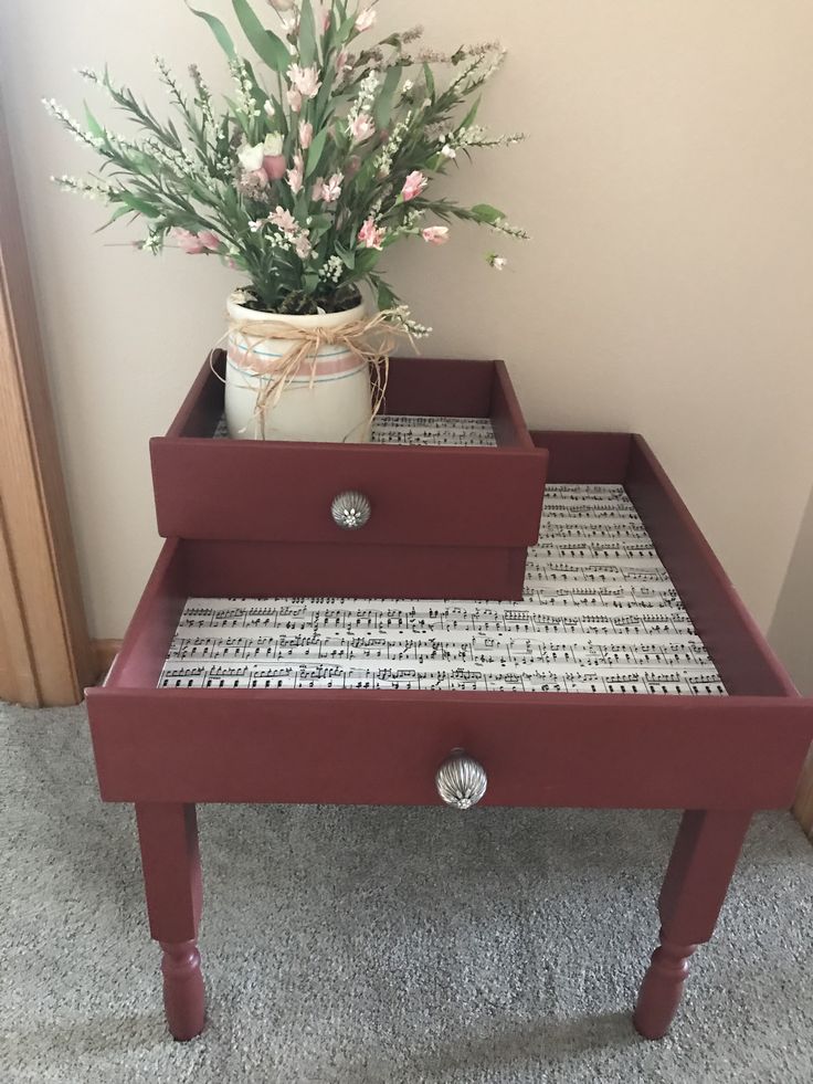 a red table with two drawers and a flower pot on the bottom one drawer is open