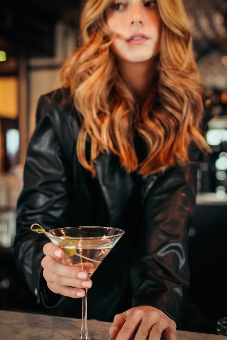 a woman sitting at a bar holding a martini