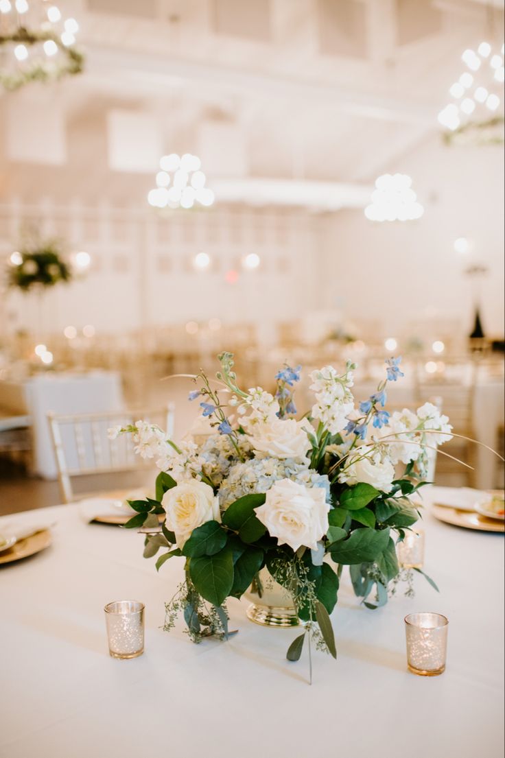 white flowers and greenery are in vases on the table at this wedding reception