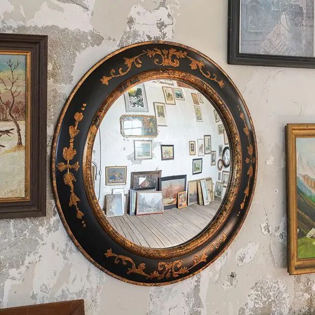 there is a mirror on the wall with many pictures in front of it that are hanging on the wall