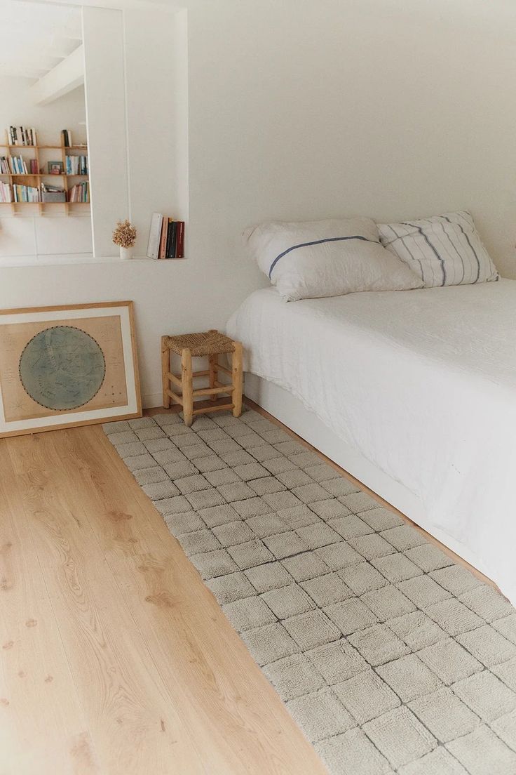 a white bed sitting next to a wooden floor in a bedroom on top of a hard wood floor