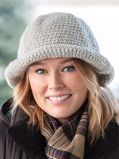 a woman wearing a knitted hat and scarf with a plaid scarf around her neck