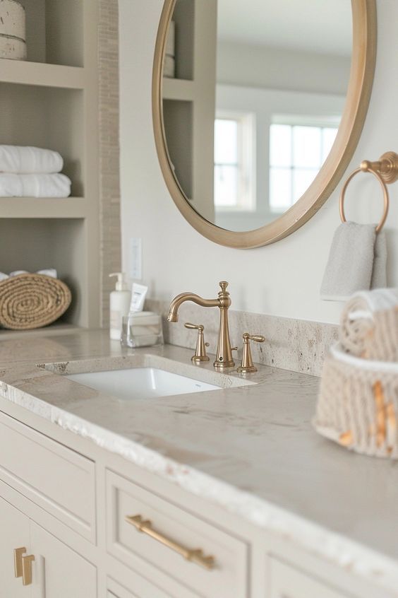 a bathroom with marble counter tops and gold faucet sink in front of a round mirror