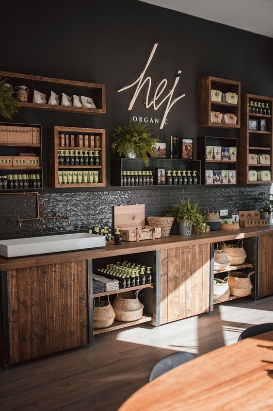 the interior of a restaurant with wooden shelves and plant displays on the wall above the counter