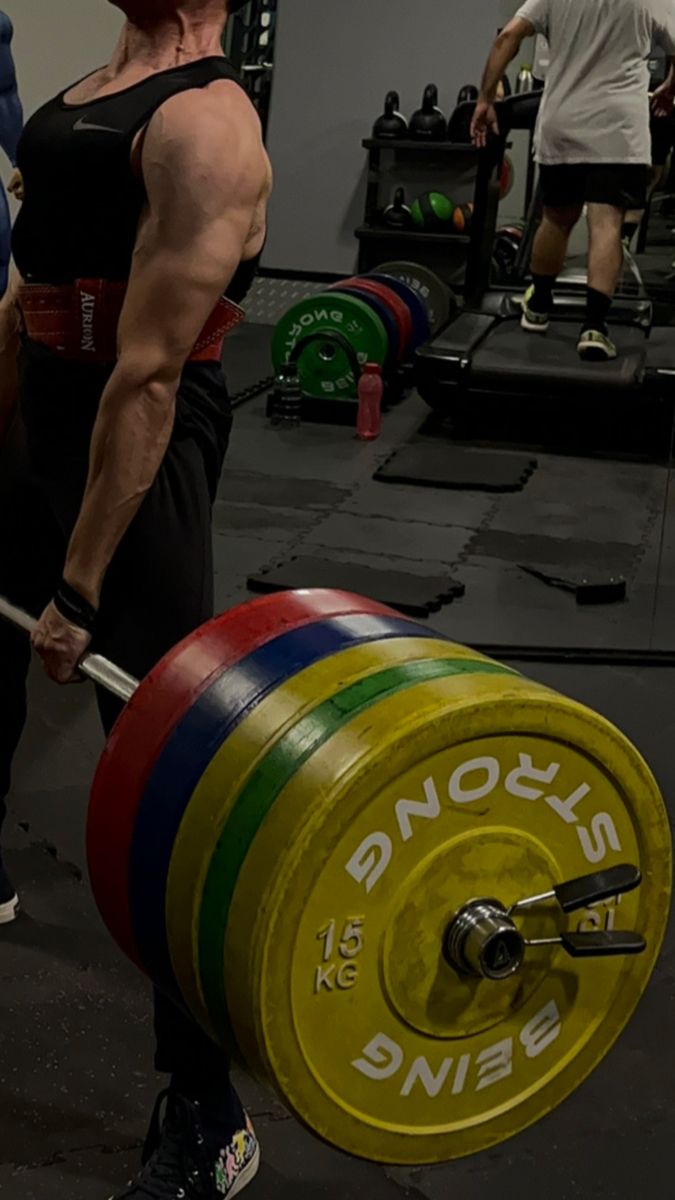 a man is lifting a barbell in the gym